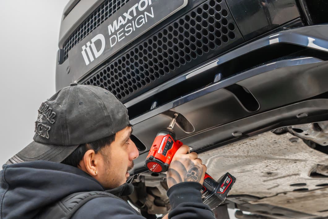 Maxton Design technician drilling to fit a front splitter under a car